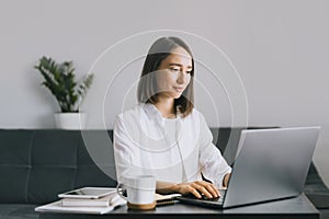 Young woman sitting at the table and using laptop.