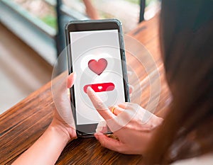 Young woman sitting at a table and using a smart phone