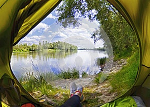 Young woman sitting in the tent while looking on the Desna river