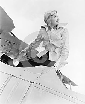 Young woman sitting on top of a biplane with gargles and hat photo