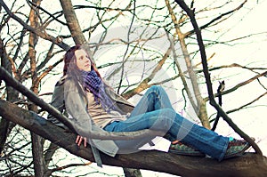 Young woman sitting on tree in the forest