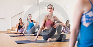 Young woman sitting in twisting asana Matsyendrasana in yoga studio