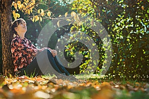 Young woman sitting under an autumn tree