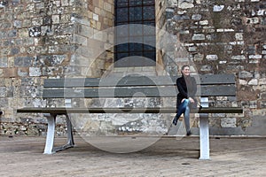 Young woman sitting in a very big bank local work of art placed close to Narbonne city hall, France