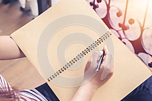 Young woman sitting on Vintage chair holding pen writing on paper and reading book