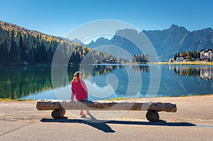 Young woman sitting on the wooden bench near the lake