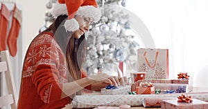 Young woman sitting wrapping Christmas gifts