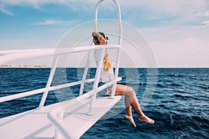 Young woman sitting on the yacht deck enjoying the moment on a sunny day. Copy space