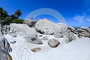 A young woman sittingon the boulders of clifton beach in the capetown area of south africa.5