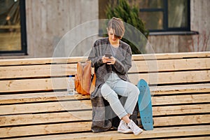 Young woman with a skateboard is resting on a 2 stage bench. lifestyle photo.