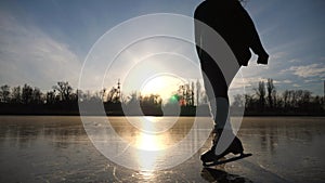 Young woman is skating on ice. Girl training alone at frozen lake or river. Lady improving his skills outdoor. Shining