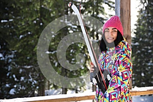 Young woman with ski wearing winter sport clothes in forest. Space for text