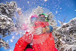 Young woman skier hugs snowboarder guy and throws snow. Concept family active winter vacations