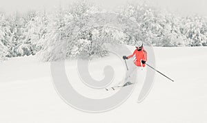 Young woman skier running downhill on ski piste