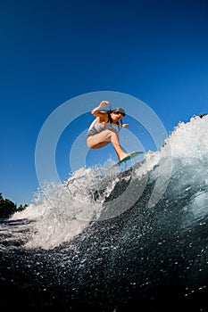 Young woman skillfully jumping on a wave on a wakesurf board photo