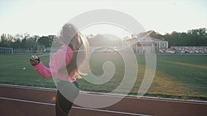 Young woman skipping rope during sunny morning on stadium track