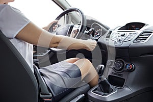 Young woman in skirt and blouse driving a car. Inside shot