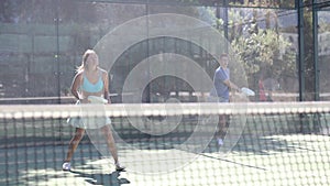 Young woman in skirt playing padel tennis on court. Racket sport training outdoors.