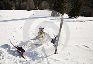 young woman on skis in a good mood fell down and cheerfully lies on the snow