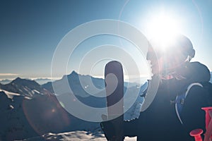 Young woman with skis near the hill against the backdrop of the sun's rays. Skier, skiing, winter sport, female