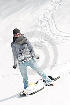 Young woman with a sled standing in the deep snow