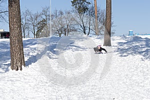 Young woman sledding in snow. laughing girl in winter clothing goes down on sleds down the hill