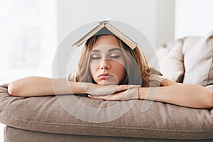 Young woman sleep on sofa with book on head