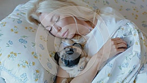 Young woman sleep sweet embracing the puppy pug