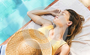 Young woman sleep tanning poolside