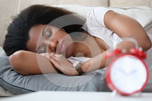Young woman is sleeping an alarm clock is on table