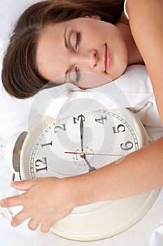 Young woman sleeping in bed with alarm clock