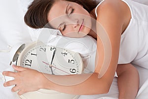 Young woman sleeping in bed with alarm clock