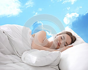 Young woman sleeping in bed. Sky on background