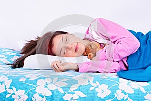 Young woman sleeping calmly in her bed hugging teddy bear