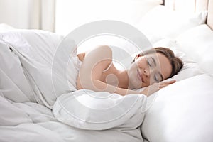 Young woman sleeping on comfortable pillow in bed