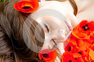 Young woman is sleeping - face on red flowers