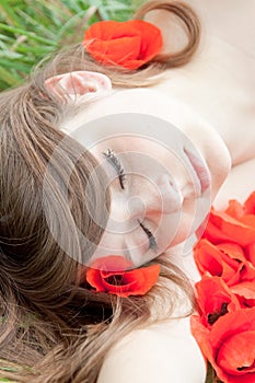 Young woman is sleeping - face on red flowers