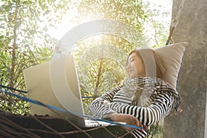 Young woman sleeping in hammock while use laptop, freelance life