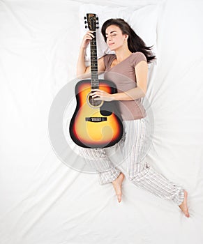 Young woman sleeping and hudding guitar