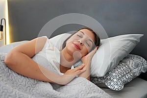 Young woman sleeping on two pillows in bed