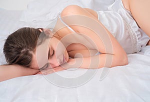 Young woman sleeping well in bed hugging soft white pillow. Girl resting, good night sleep. Sweet dreams.