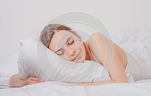 Young woman sleeping well in bed hugging soft white pillow. Girl resting, good night sleep. Woman sleeping. Beautiful