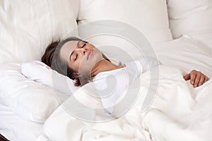 Young woman sleeping well in cozy bed with white linen