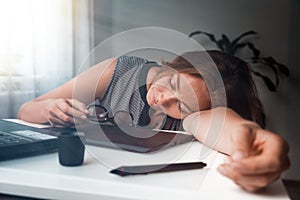 Young woman sleeping in the workplace. Fatigue and overload in office work. Morning light