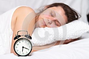 Young woman sleeps in the bed and waits for alarm clock call. A woman wakes up in bed