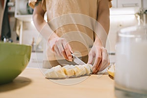 Young woman slices a banana for a light, healthy breakfast.