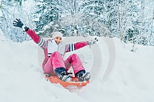 Young woman slide down from snow slope sitting in one slide.Winter activities concept image