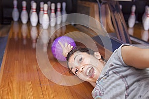 Young woman sliding down a bowling alley