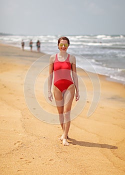 Young woman with slim body, wearing red swimsuit and sunglasses