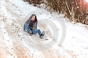 Young woman slipped and fell in the snow road.